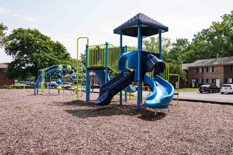 A playground with a blue slide and yellow railing.