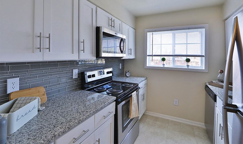 a kitchen with white cabinets and granite counter tops