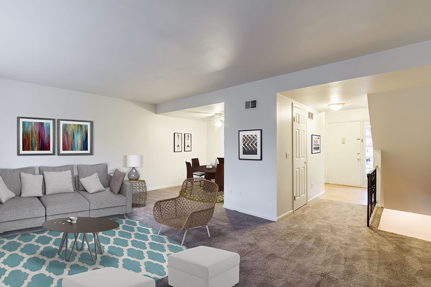 a living room with a couch and a chair and a hallway to a dining room