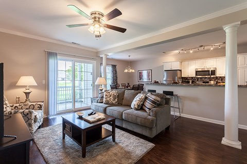 A living room with a grey couch and a ceiling fan.