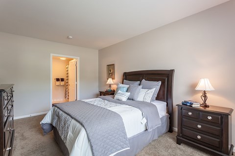 A bedroom with a large bed and a nightstand with a lamp.
