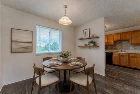 A dining room with a table set for two and a view of the backyard.
