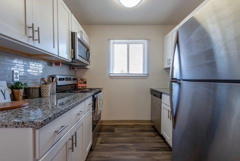A kitchen with a stainless steel refrigerator and wooden floors.