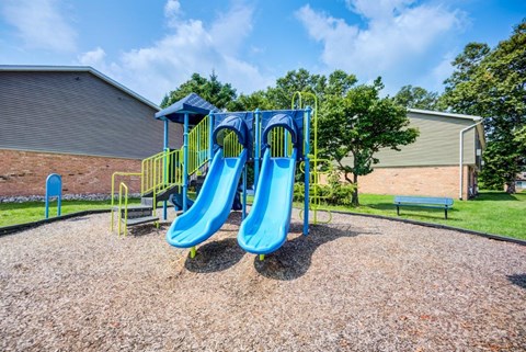 A playground with a blue slide and yellow handrails.