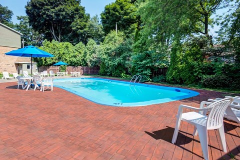 A pool surrounded by trees and chairs.