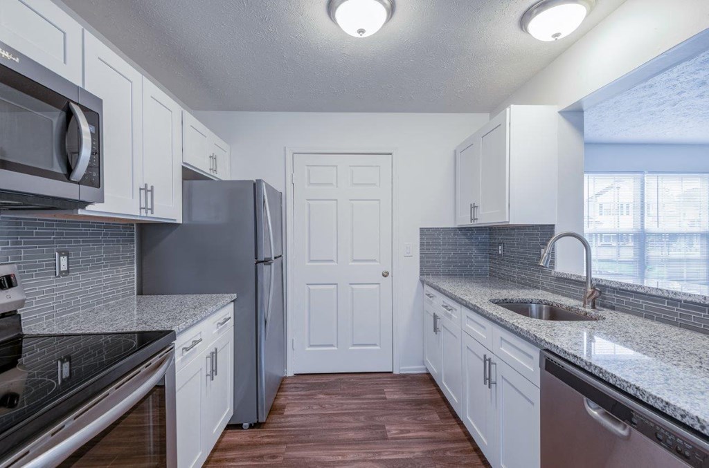 a kitchen with white cabinets and a stainless steel refrigerator