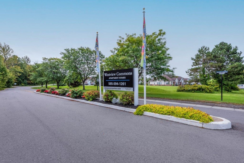 the sign at the end of a road with flowers and flags