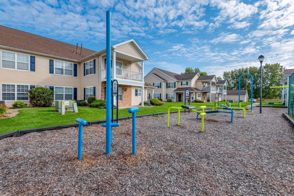 a playground with blue and yellow poles in front of apartment buildings