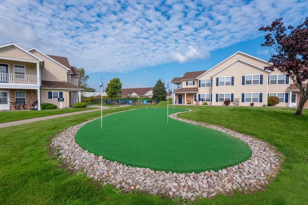 a circular green lawn with houses in the background