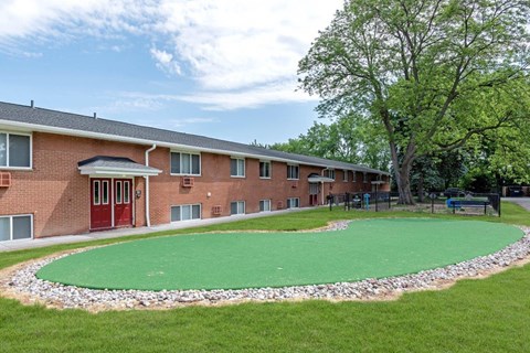 a green circle of grass in front of a brick building