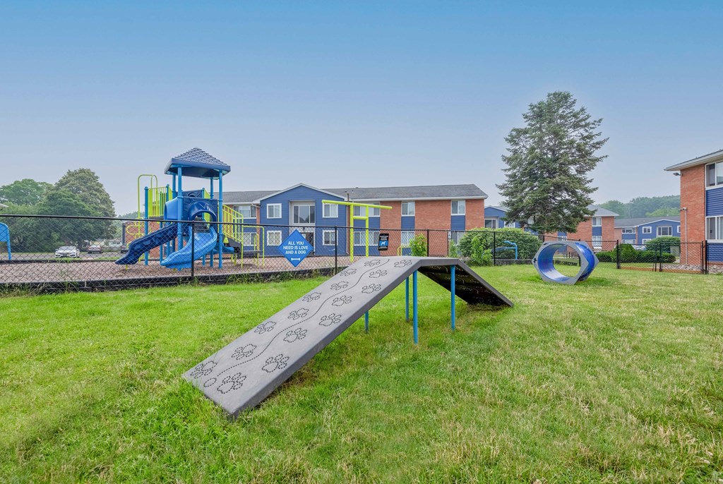 a playground with a slide and playset in front of a school