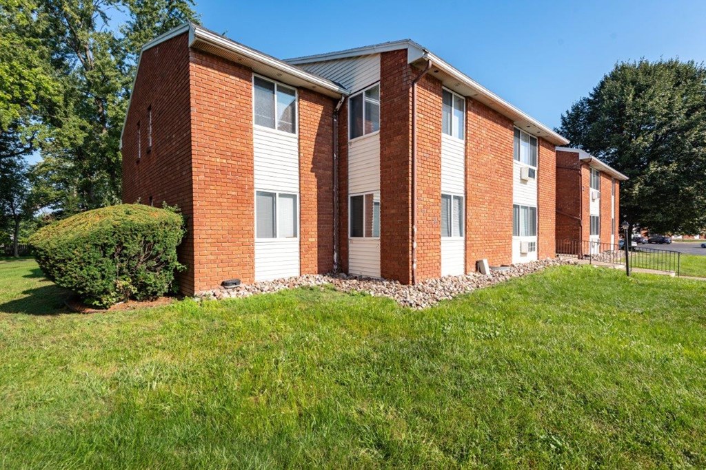 a brick apartment building with green grass in front of it
