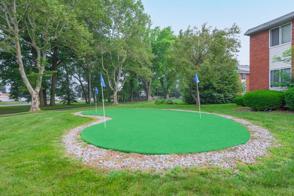 a putting green in the middle of a yard in front of a building