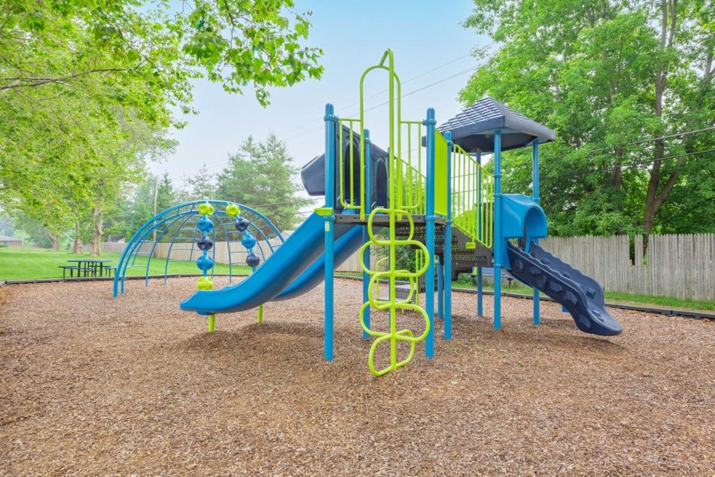 a playground with a swing set and slides at a park