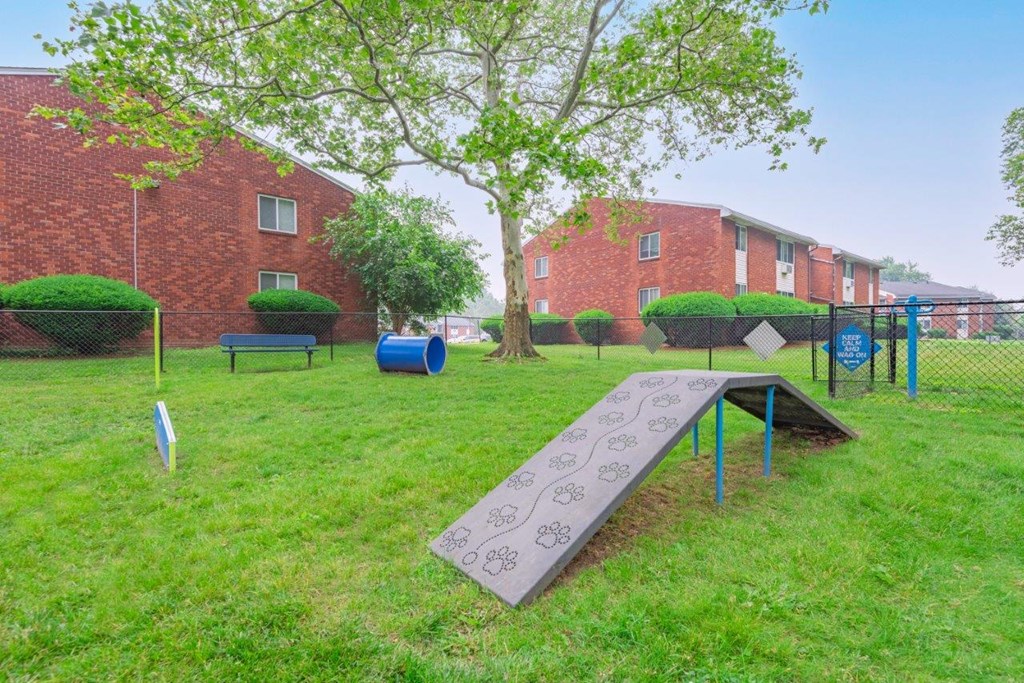 a playground with a ramp in a yard in front of a brick building