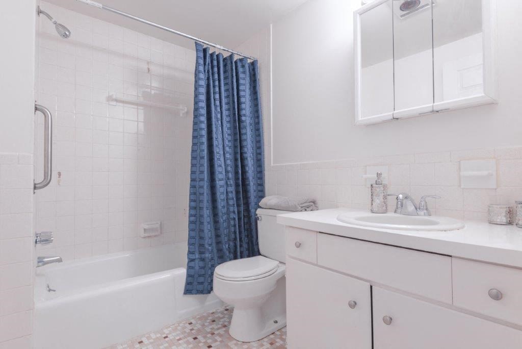 a white bathroom with a shower toilet and sink