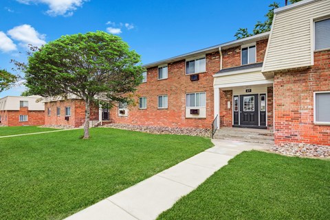 an apartment building with a lawn and a sidewalk