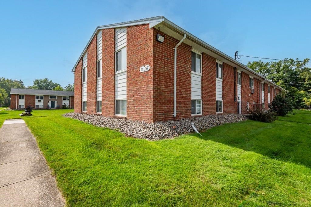 a brick building with green grass and a sidewalk