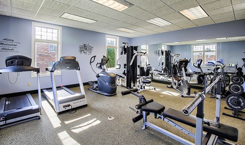 a gym with cardio equipment and weights in a building with windows