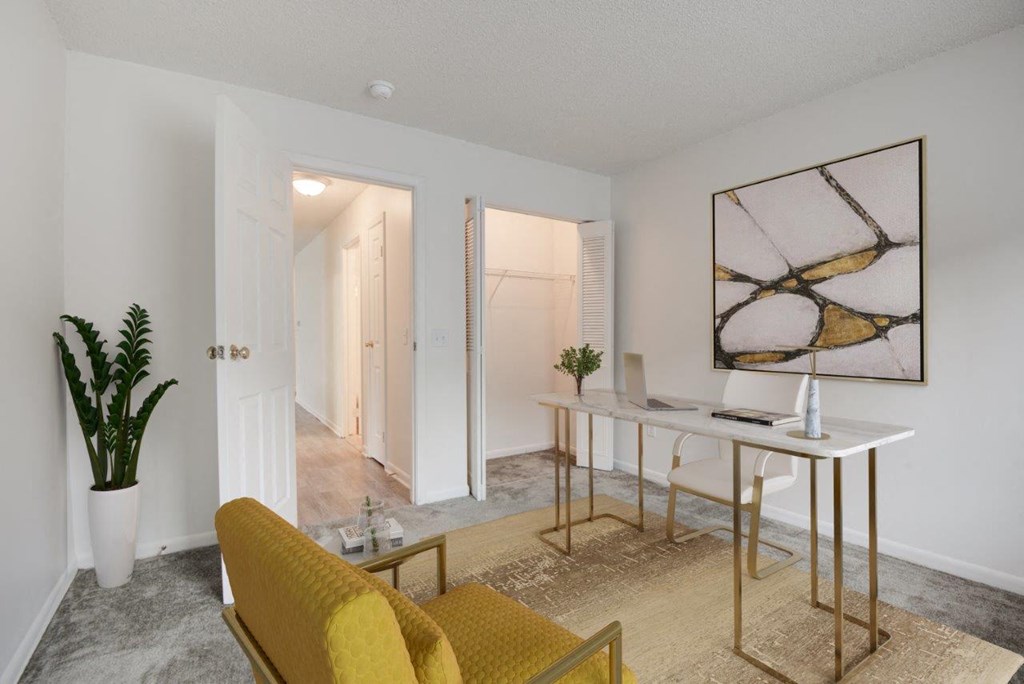 a living room with a desk and a door to a hallway