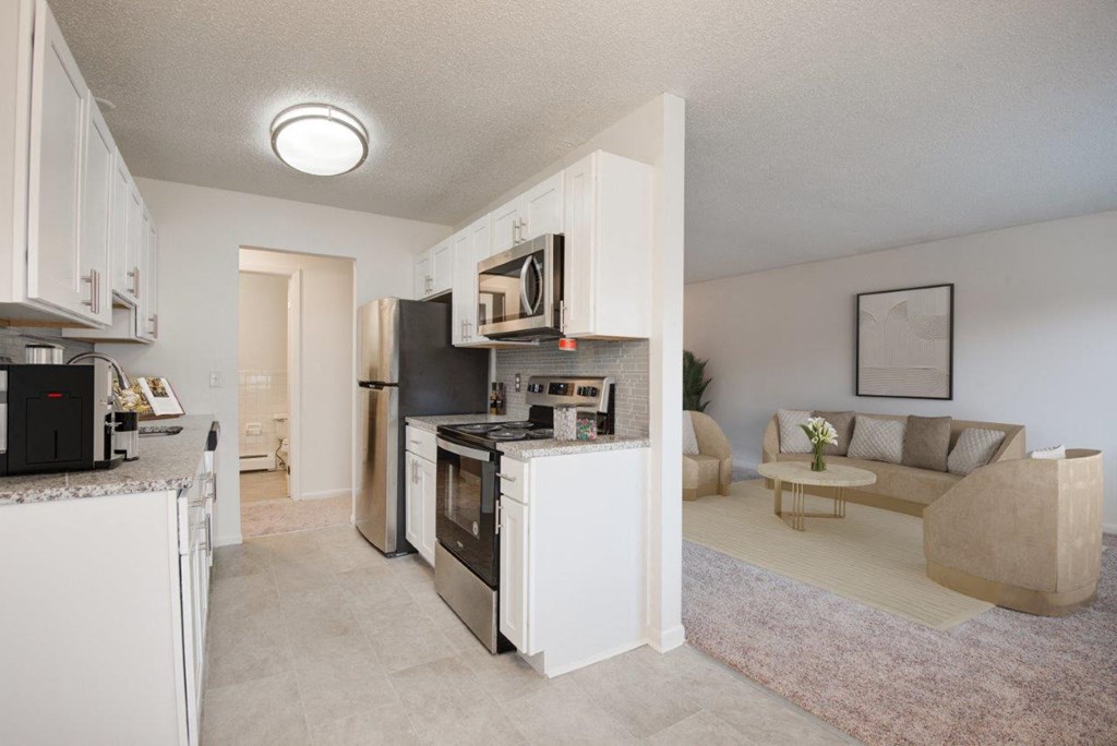 a kitchen and living room with a stove refrigerator and microwave