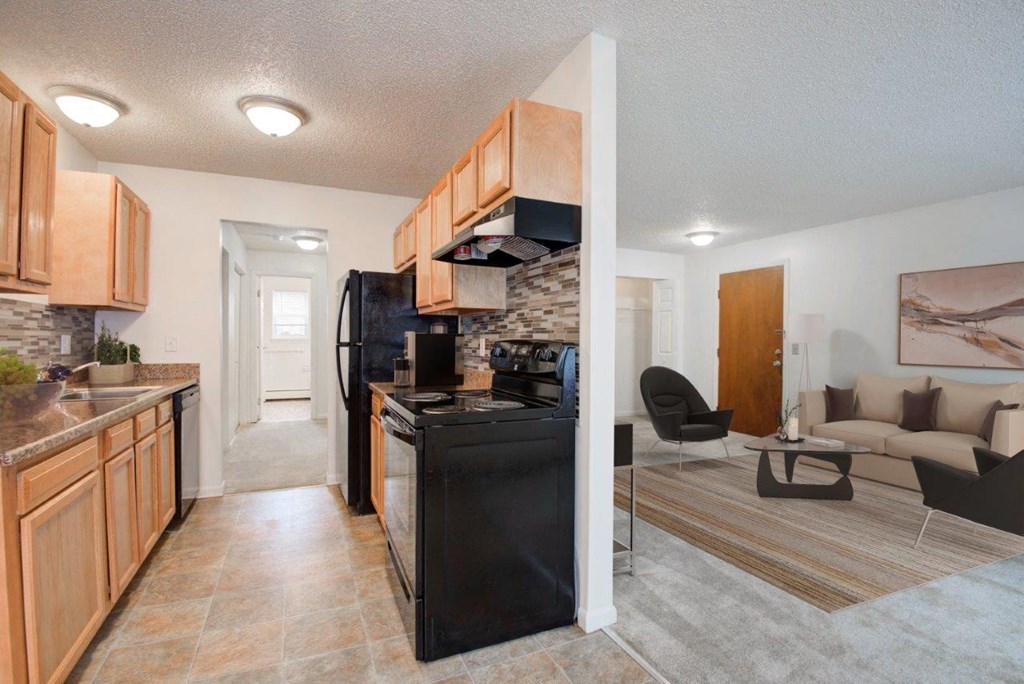 a kitchen and living room with a black stove and refrigerator