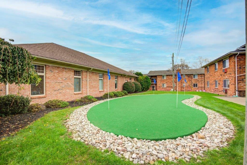 a putting green in front of a brick building