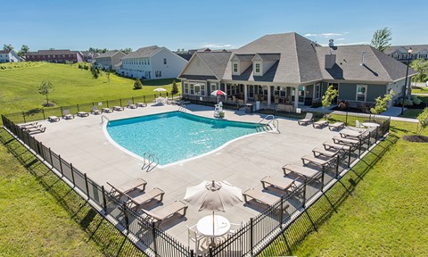 a swimming pool with chairs and umbrellas in front of a house