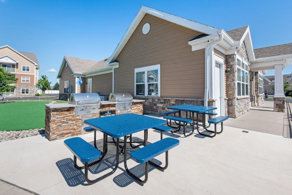 our picnic tables are in front of our building with a grill and barbecue