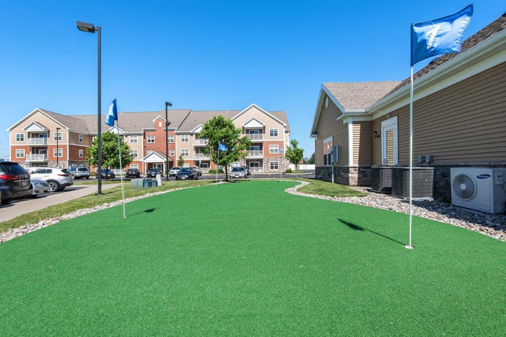 a putting green in front of a building with flags