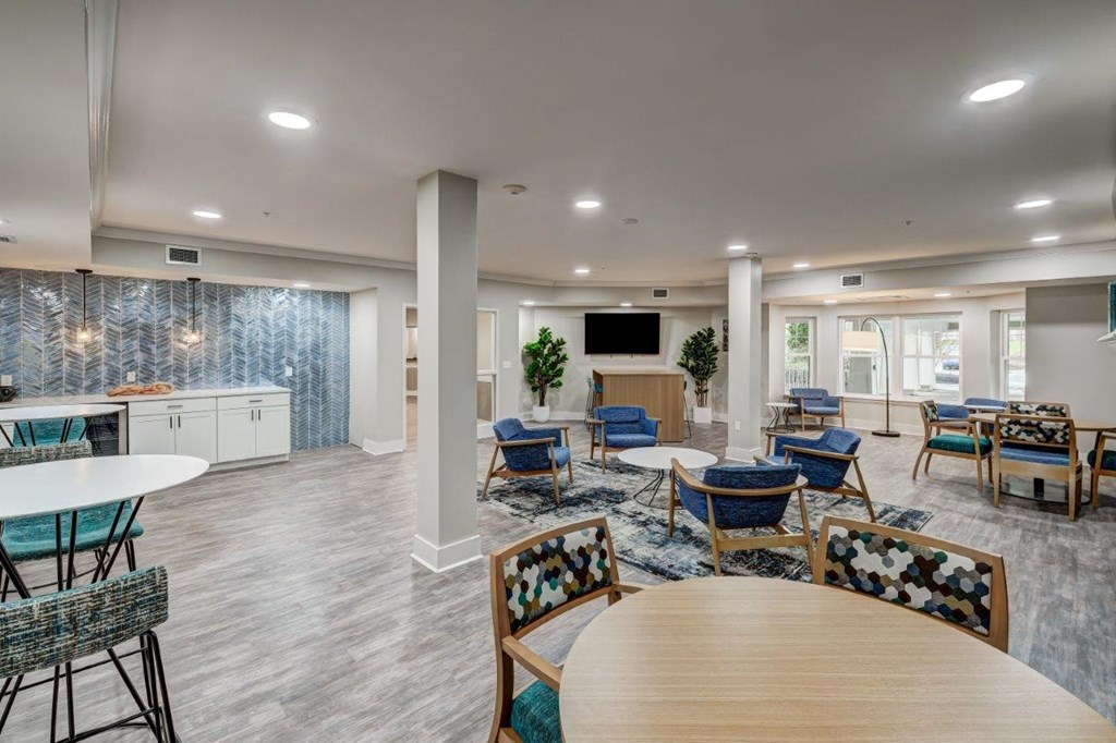 a community room with tables and chairs and a kitchen