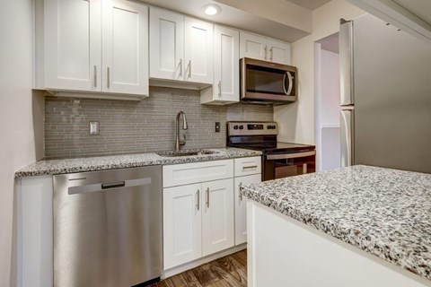 a white kitchen with granite counter tops and stainless steel appliances