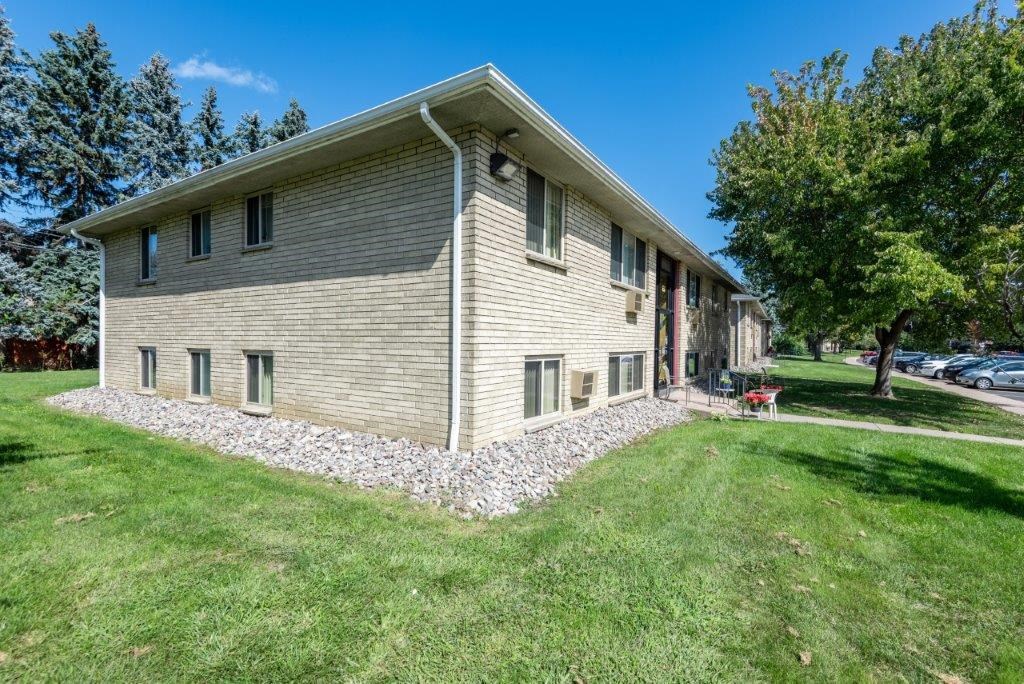 a large white house with a stone wall in the grass