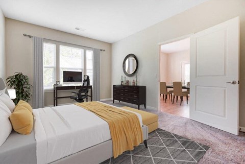 A bedroom with a bed, a desk, a chair, and a mirror.