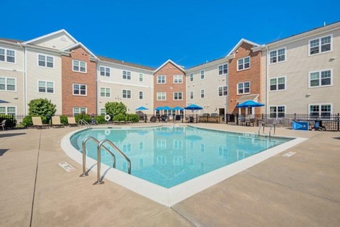 A large swimming pool is surrounded by apartment buildings.