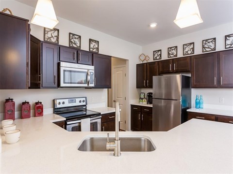 A kitchen with dark brown cabinets and a stainless steel refrigerator.