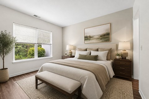 A bedroom with a large bed, a potted plant, and a painting on the wall.