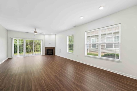 A spacious room with wooden flooring and a fireplace.
