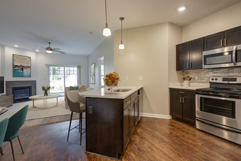 A modern kitchen with dark wood cabinets and stainless steel appliances.