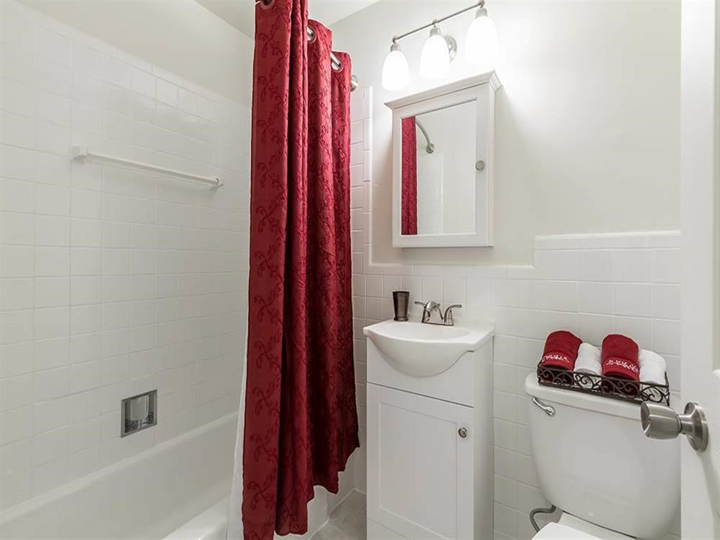 a bathroom with a white toilet and a red shower curtain