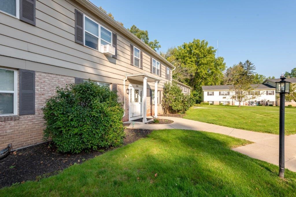 a side view of a house with a yard and sidewalk