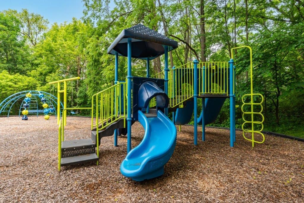 a playground with a blue slide and a yellow swing set
