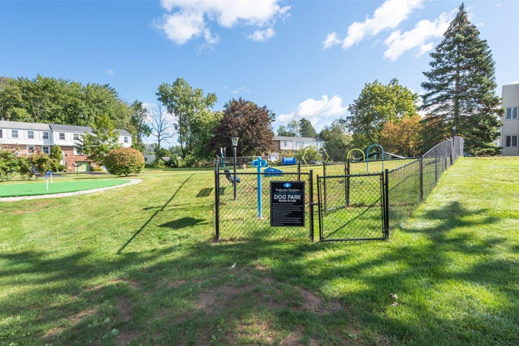 a fenced in park with a playground and a sign