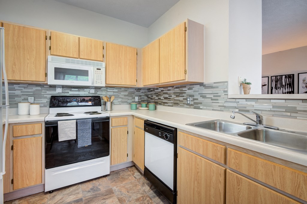 a kitchen with wood cabinets and white appliances and a sink