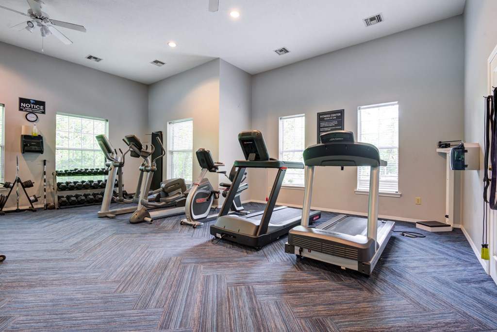 a gym with cardio equipment on the floor and windows