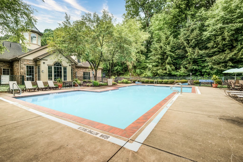 a swimming pool with chairs around it in front of a house