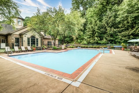 a swimming pool with chairs around it in front of a house