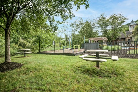 a group of picnic tables in a park next to a fence