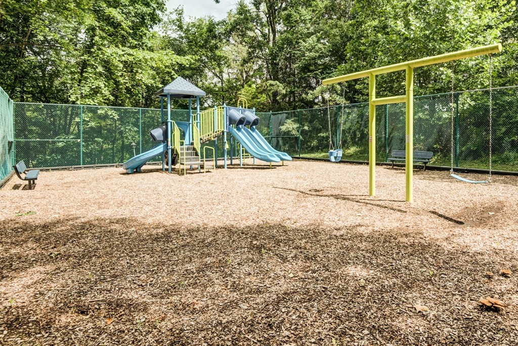 a playground with a slide and swings in a park