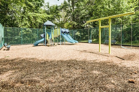 a playground with a slide and swings in a park